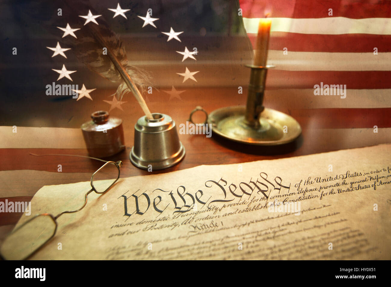 US Constitution with quill pen, ink, glasses, candle and flag with thirteen stars Stock Photo