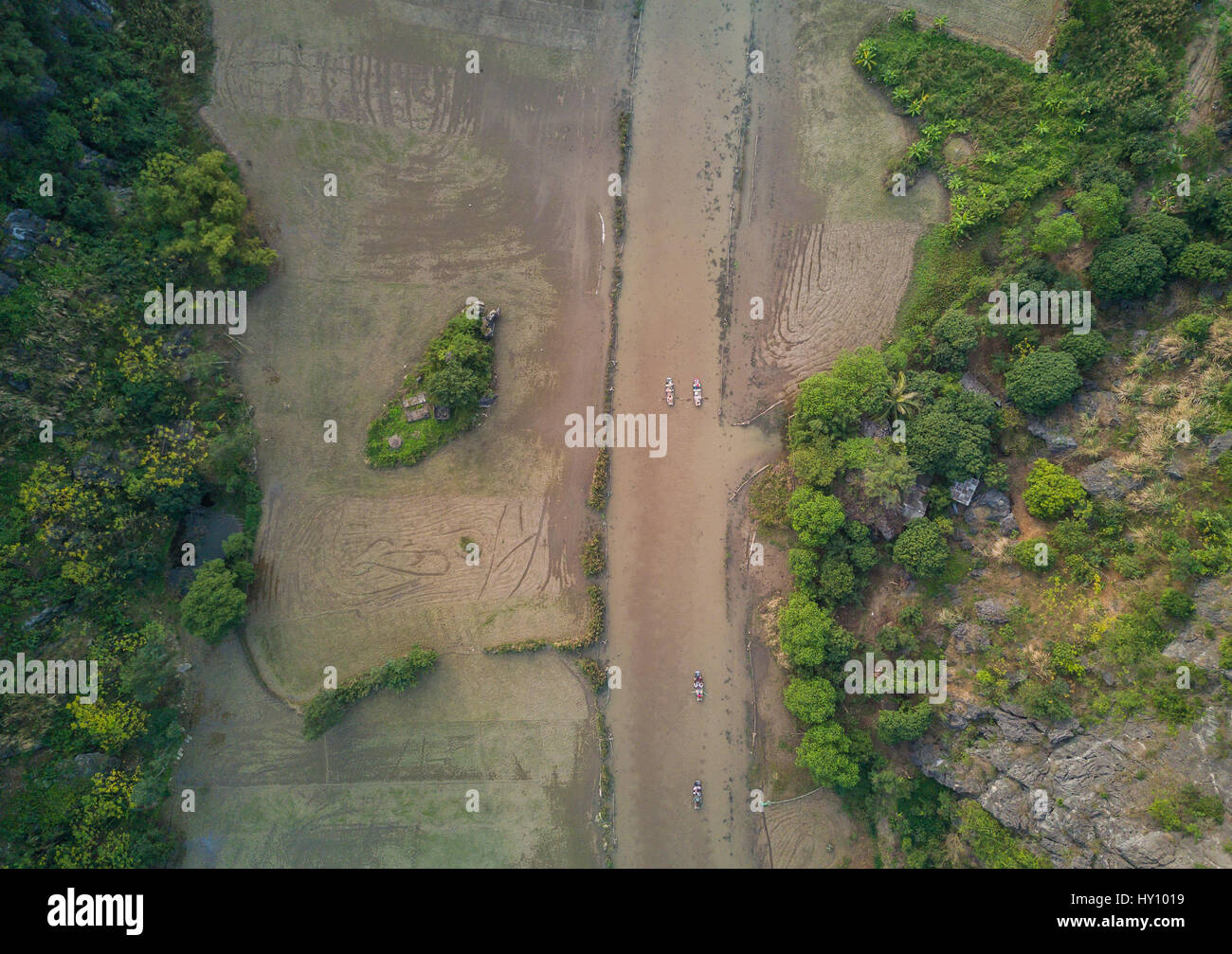 Aerial image taken above Ninh Binh. Below tourists enjoy the scenic views by river boats. Normally the river winds it's way through rice fields. Stock Photo