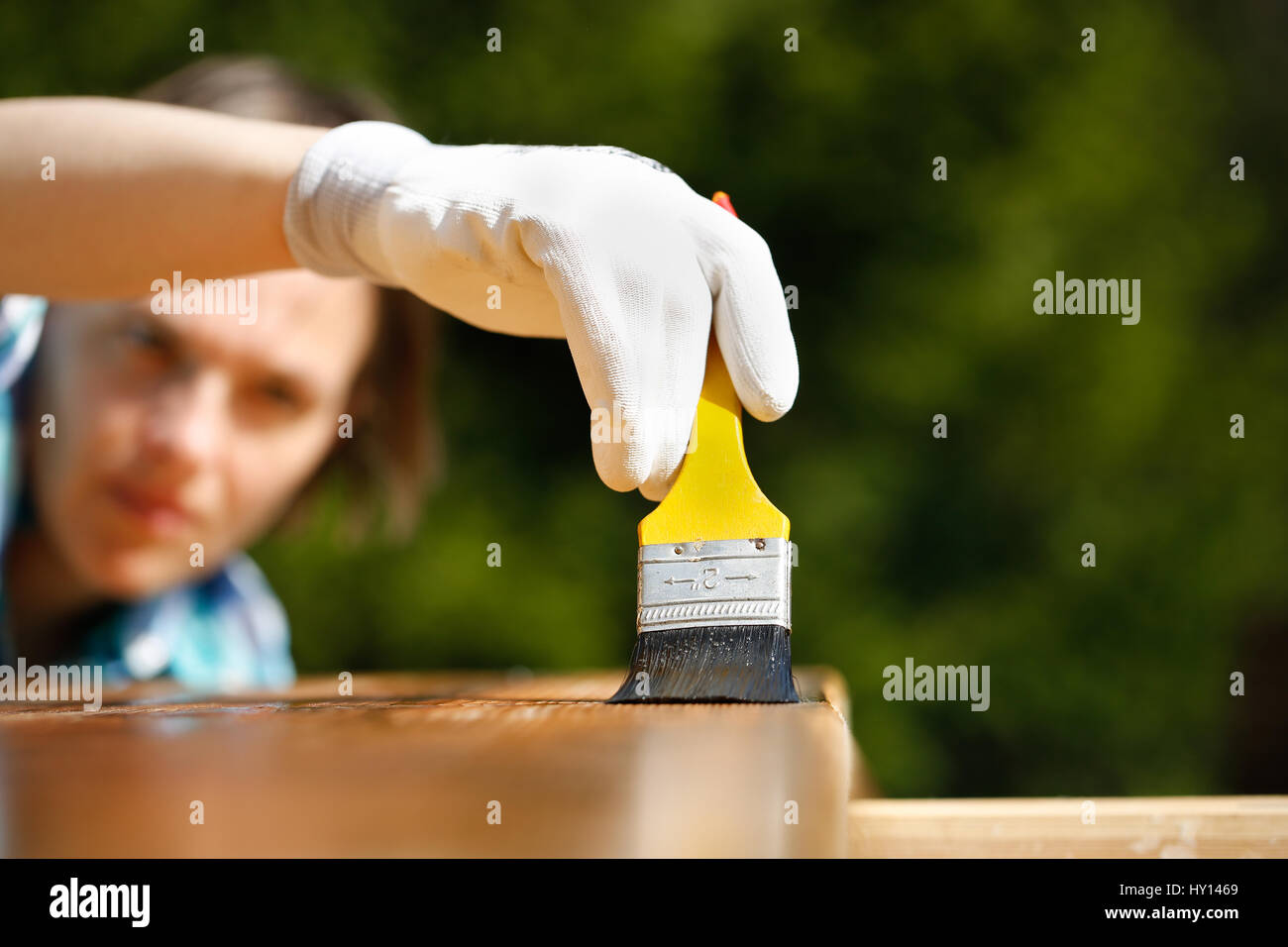Woman carpenter inspecting her work after treating wood with protection