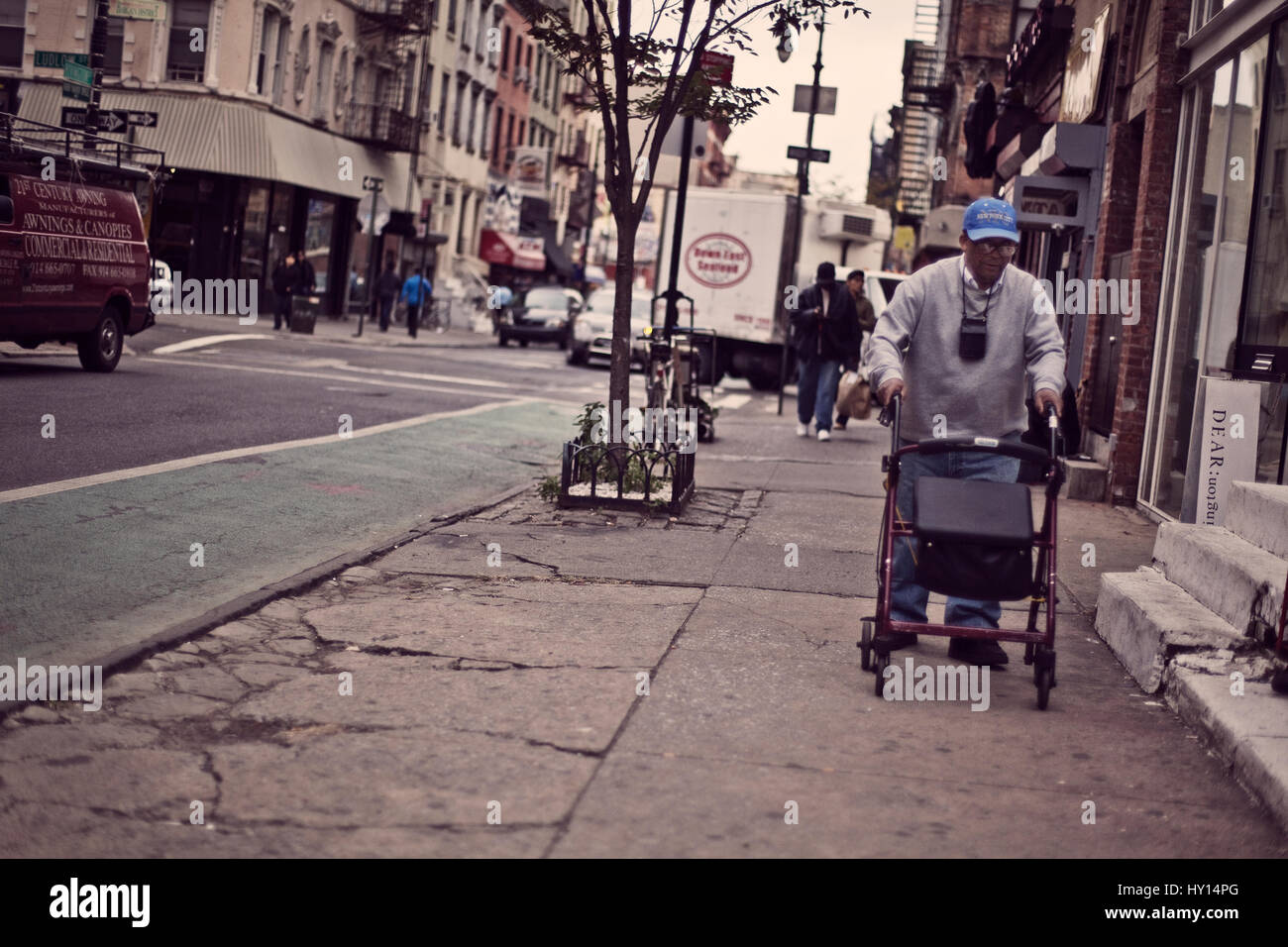 An old man is using his wheeled walker to get around in New York