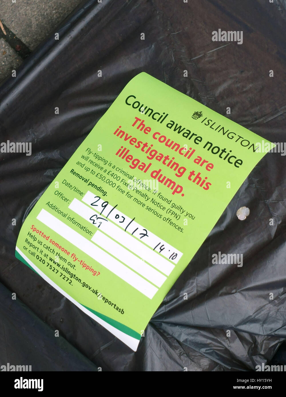 Council notice on fly-tipped rubbish bag in Islington, London Stock Photo