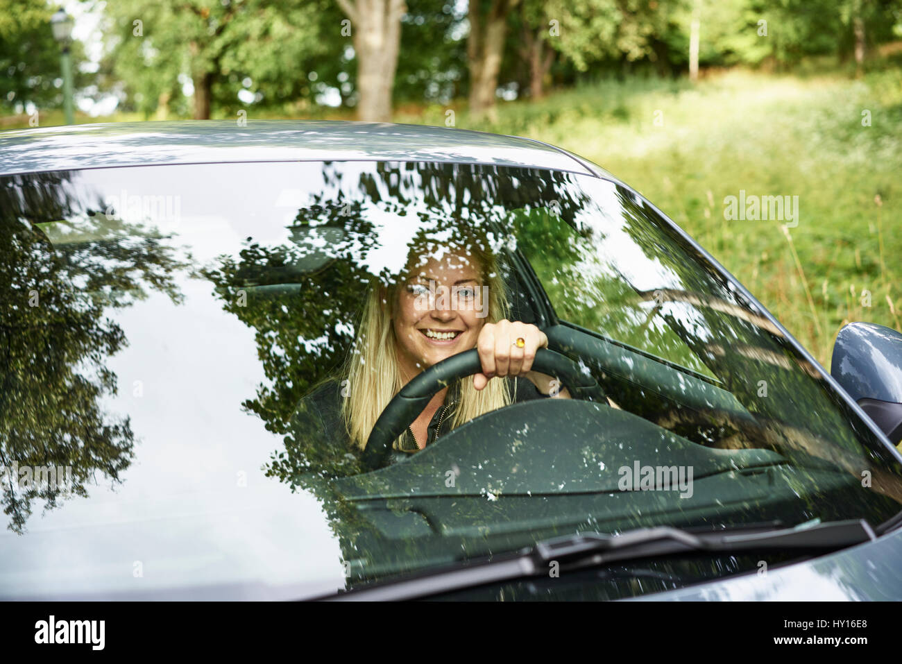 Sweden, Uppland, Smiling woman travelling by car in countryside Stock Photo