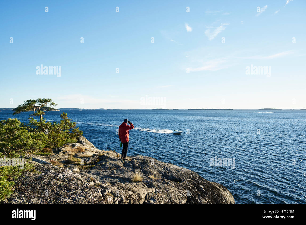 Sweden, Stockholm Archipelago, Varmdo, Bjorno, Man looking at view, motorboat in sea Stock Photo