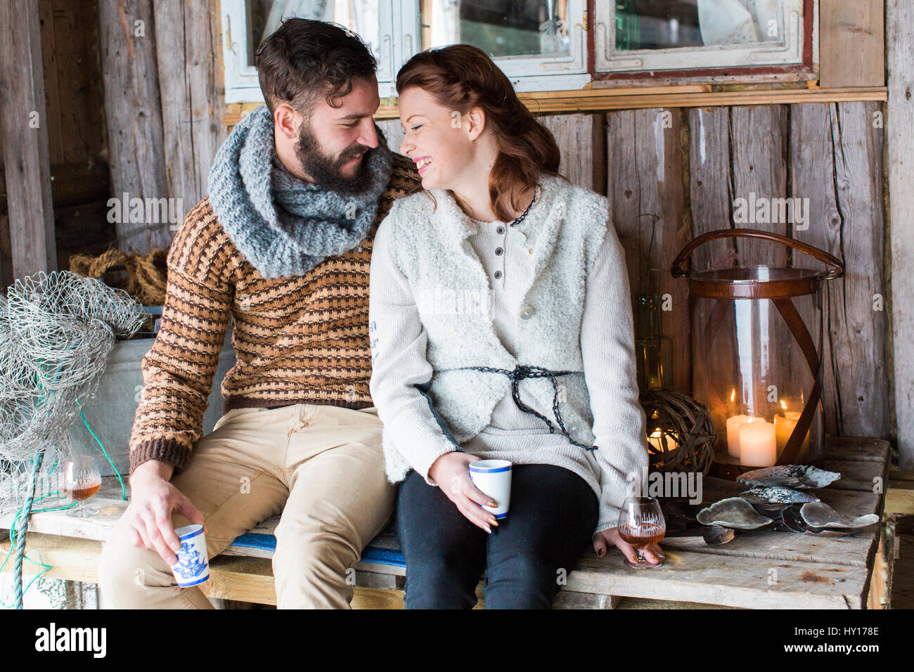 Sweden, Young couple sitting on wooden table and talking Stock Photo