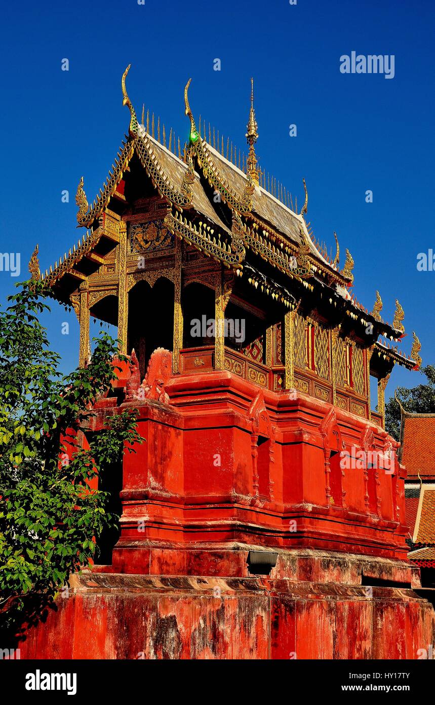 Lamphun, Thailand - December 28, 2012: Library repository built upon a red sandstone base with gilded roof and chofah ornaments at Wat Phra That Harip Stock Photo