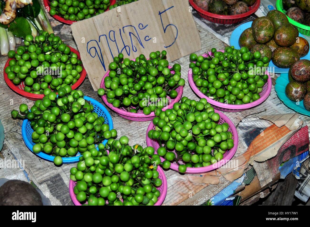 Lamphun, Thailand - December 28, 2012:  Dishes of green Makhan, small Asian eggplants, are displayed in dishes at the Mea Tha Market Stock Photo