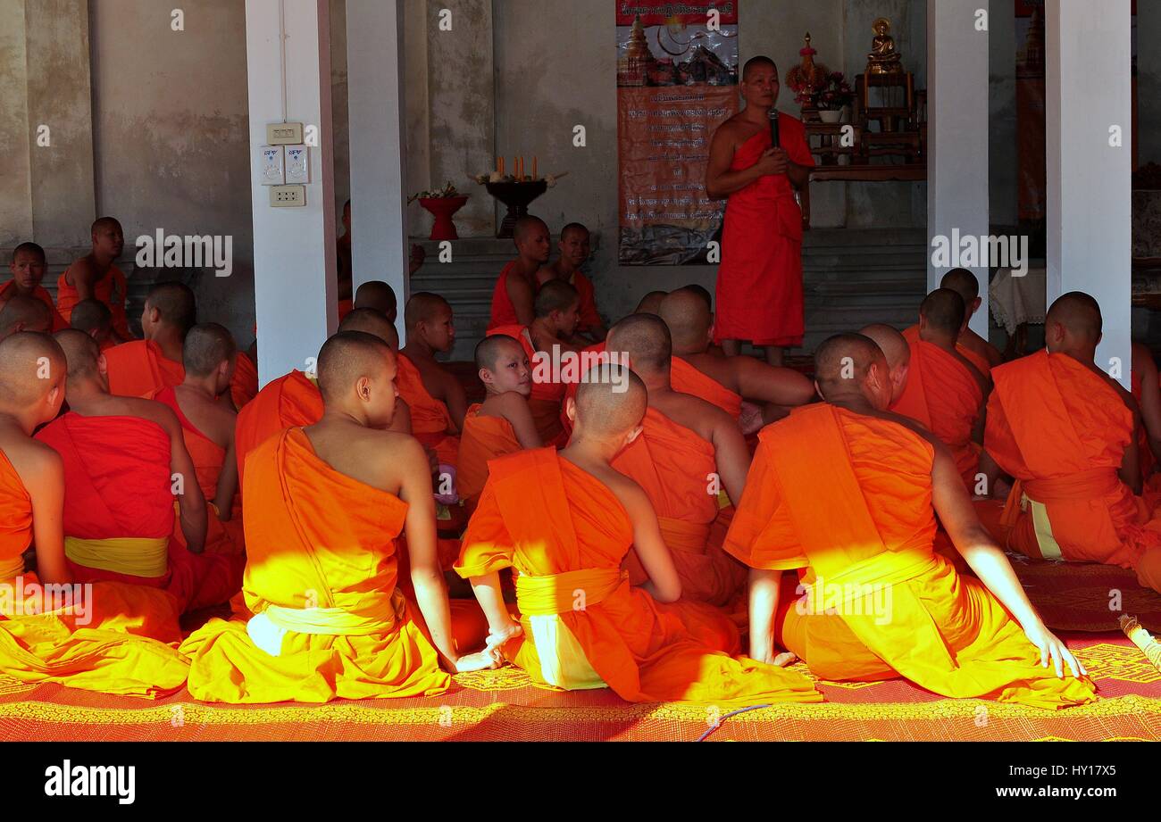 Lamphun, Thailand - December 28, 2012:  A large group of monks in orange robes sitting in a temple pavilion at Wat Phra That Haripunchai Maha Viham Stock Photo