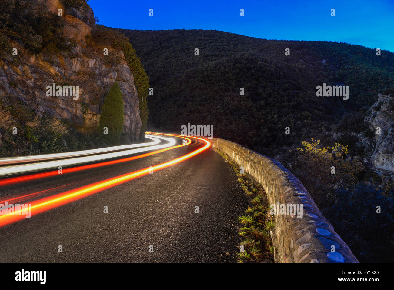 Time exposure of car lights rounding a corner, on a mountain pass at night. Pyrenees mountains, Molitg les Bains, France. Stock Photo