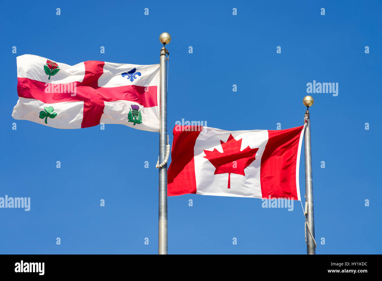 Canadian flag and Montreal city flag waving over blue sky Stock Photo