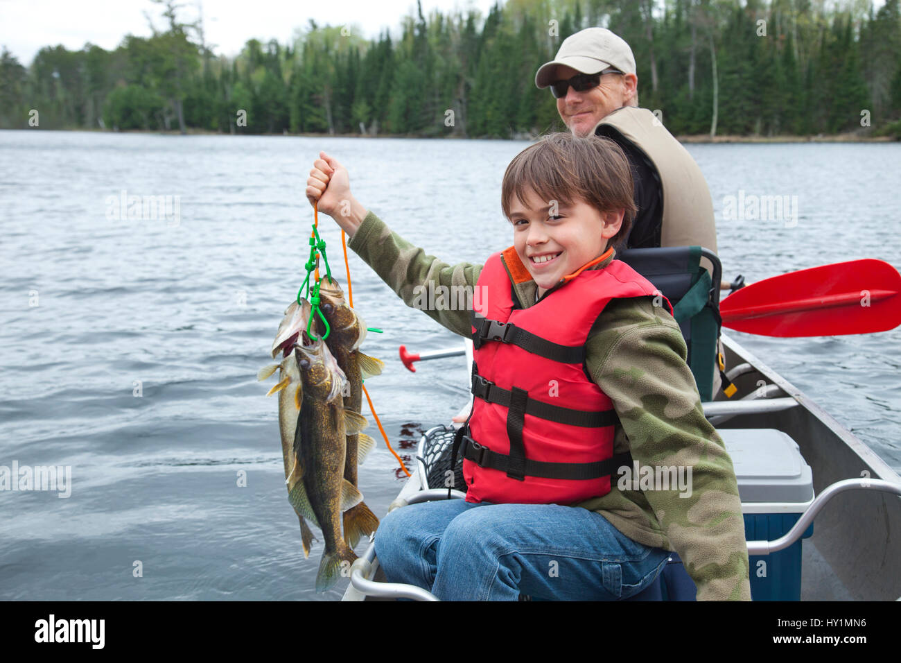 A young caucasian fisherman proudly holds up a stringer of walleyes Stock Photo