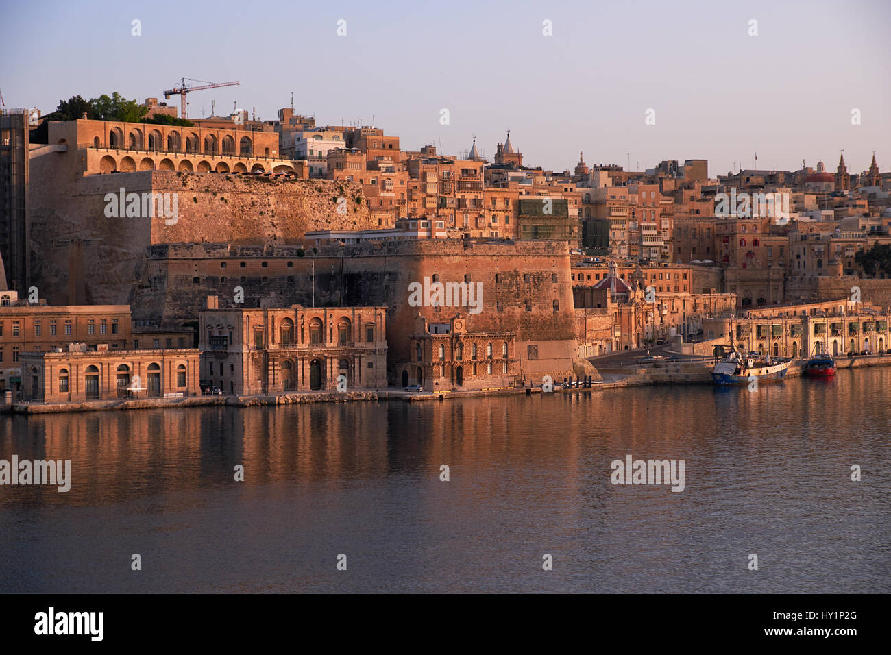 The early morning view of Valletta capital city fortifications with Fort Lascaris and Upper and Lower Barrakka Gardens  from the water of Grand Harbou Stock Photo