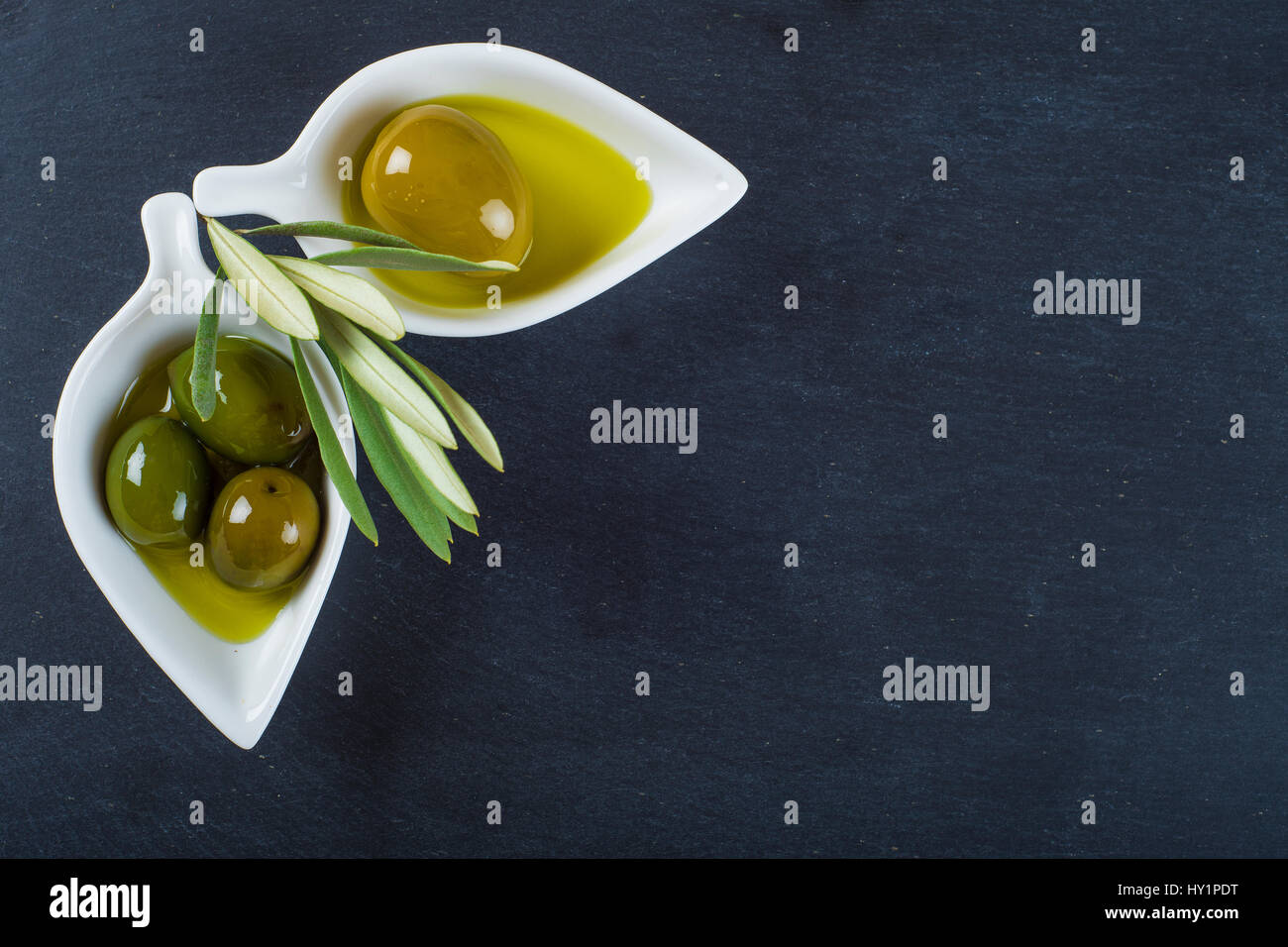 Extra virgin olive oil and green olives on a blackboard with a copy ...