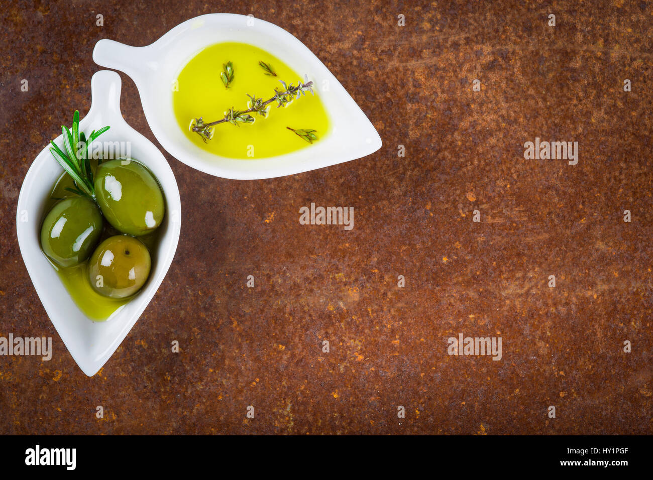 Extra virgin olive oil and green olives on an old iron surface with a
