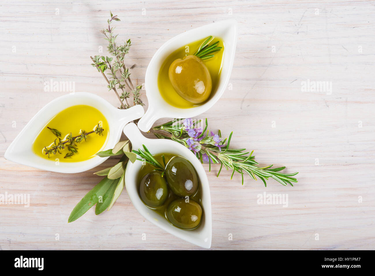 Extra virgin olive oil and green olives on a white wooden background ...