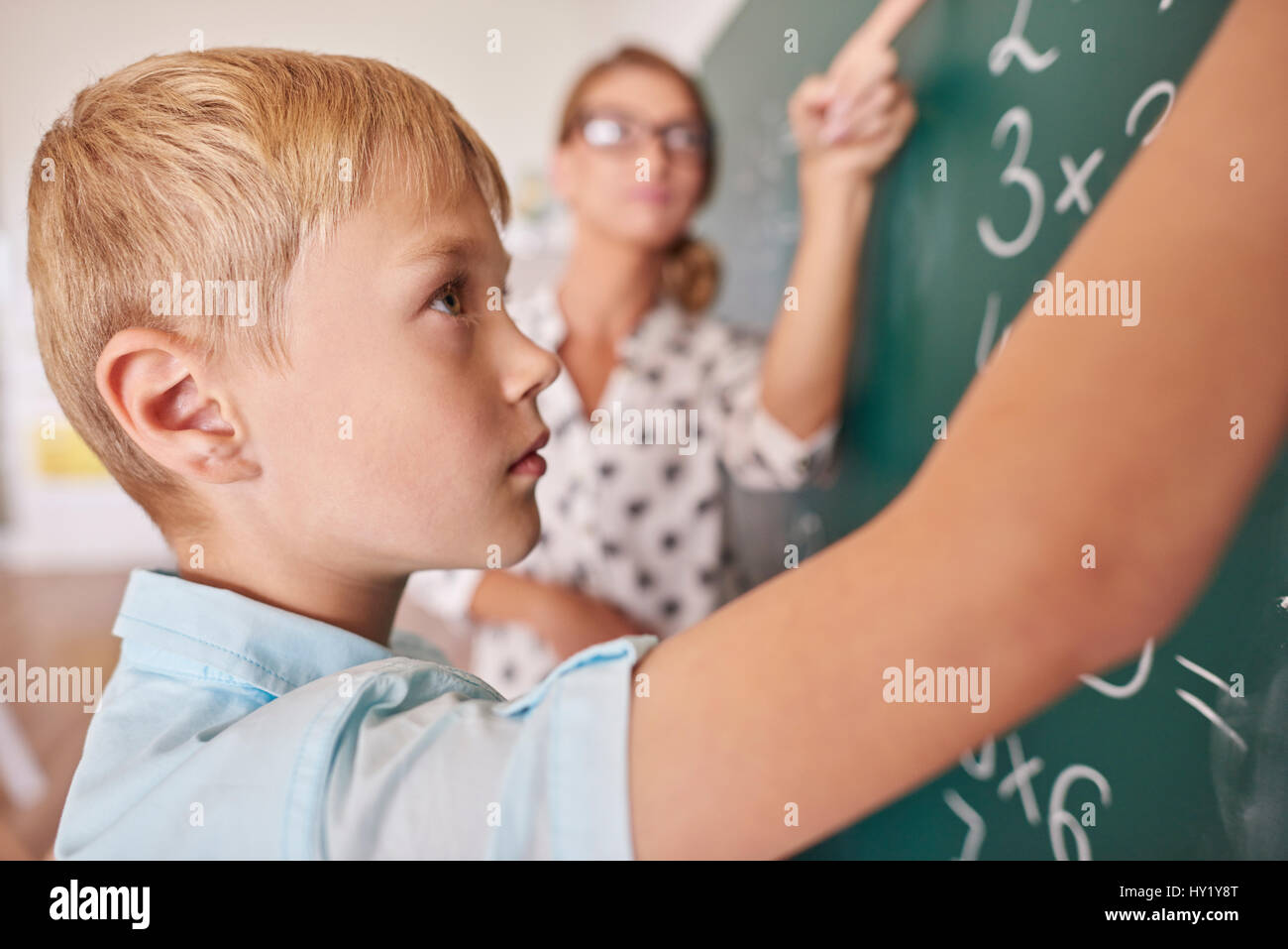 Student boy doing math problem on chalkboard Stock Photo