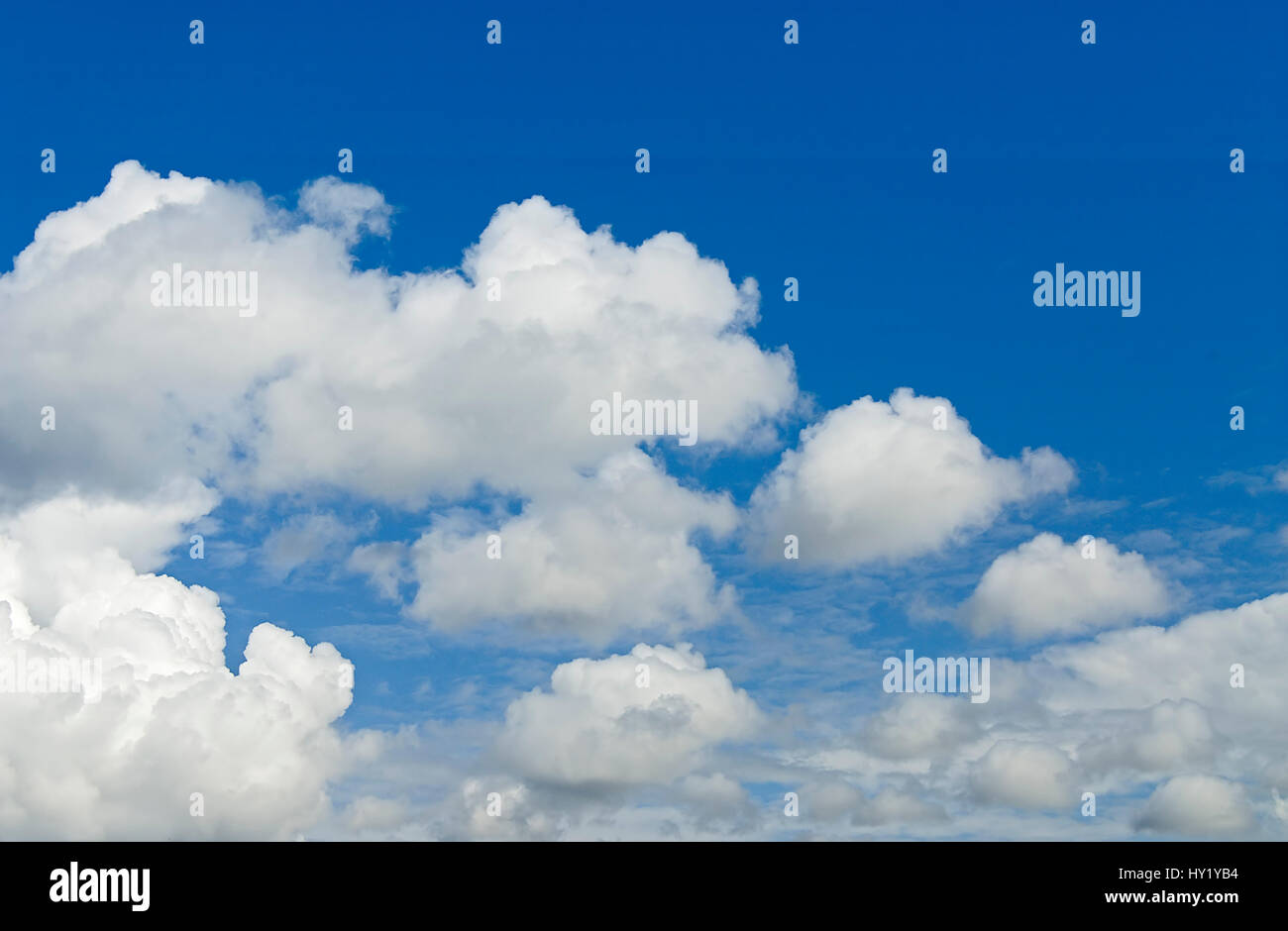 This stock photo shows a perfect blue sky partly covered with cumulus clouds. The image was taken on a sunny morning. Stock Photo