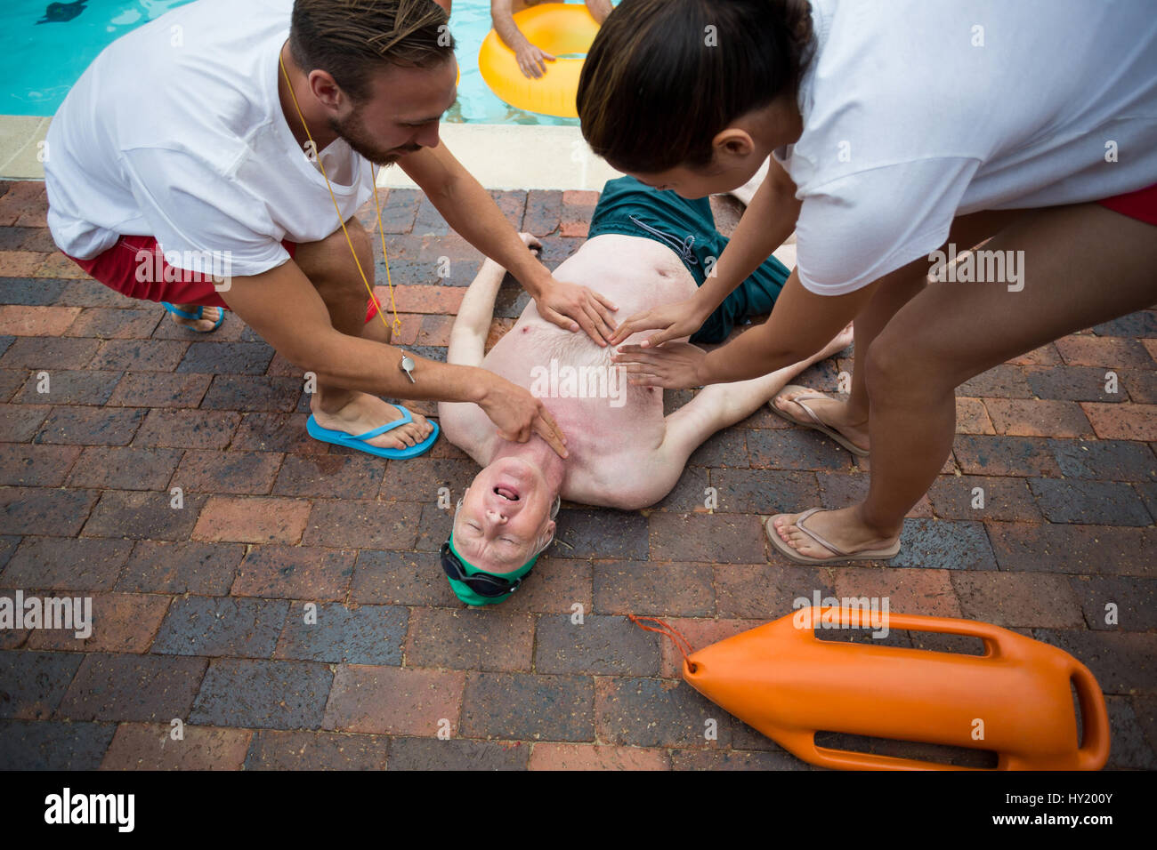 High angle view of rescue workers saving unconscious senior man at poolside Stock Photo