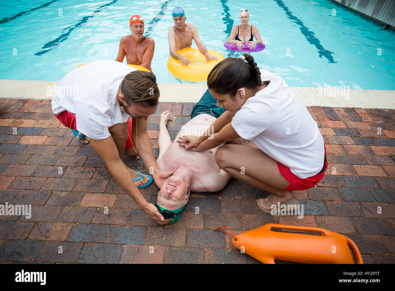 High angle view of rescue workers helping unconscious senior man at poolside Stock Photo