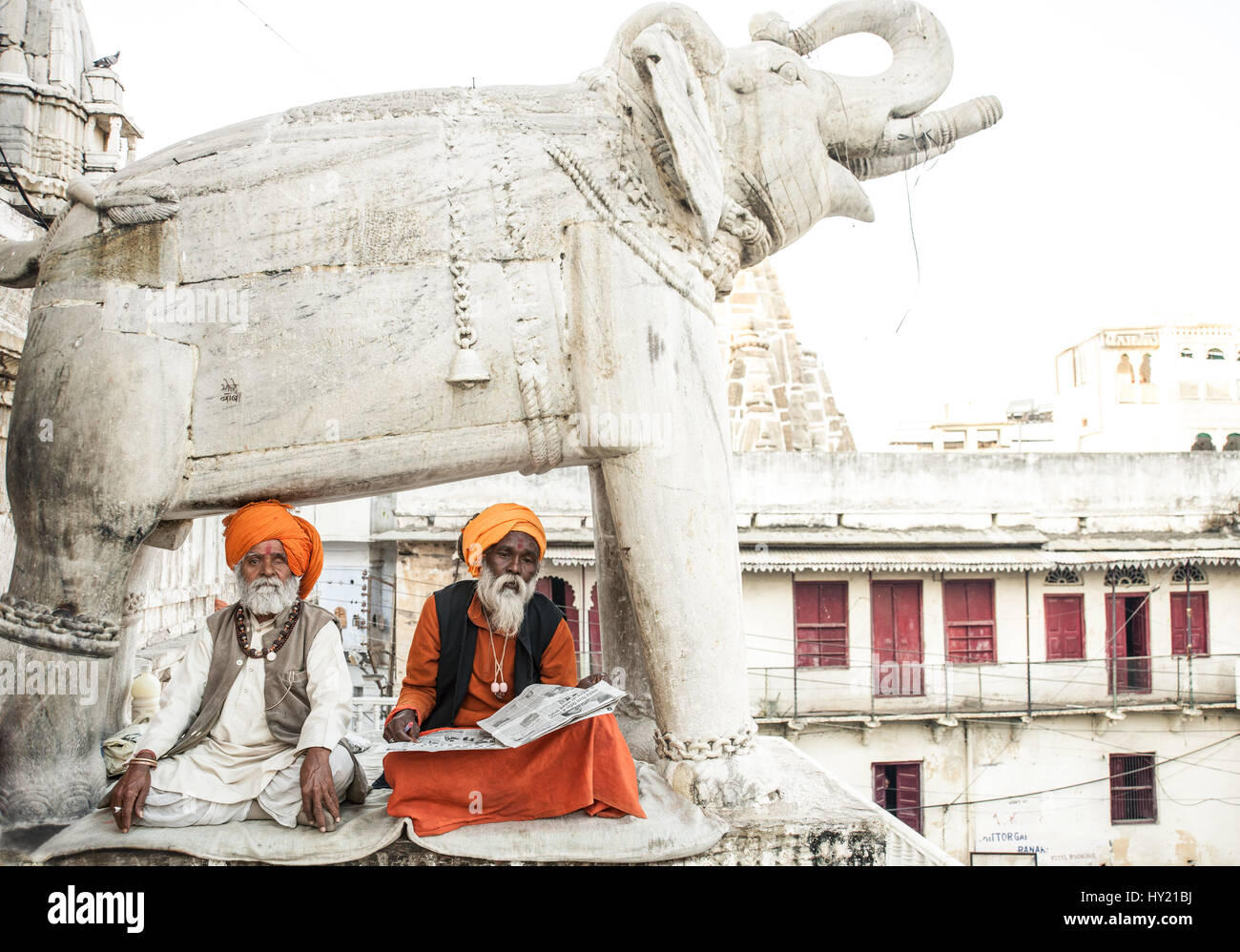 A pair of gentlemen sitting beneath the elephant statue guarding the