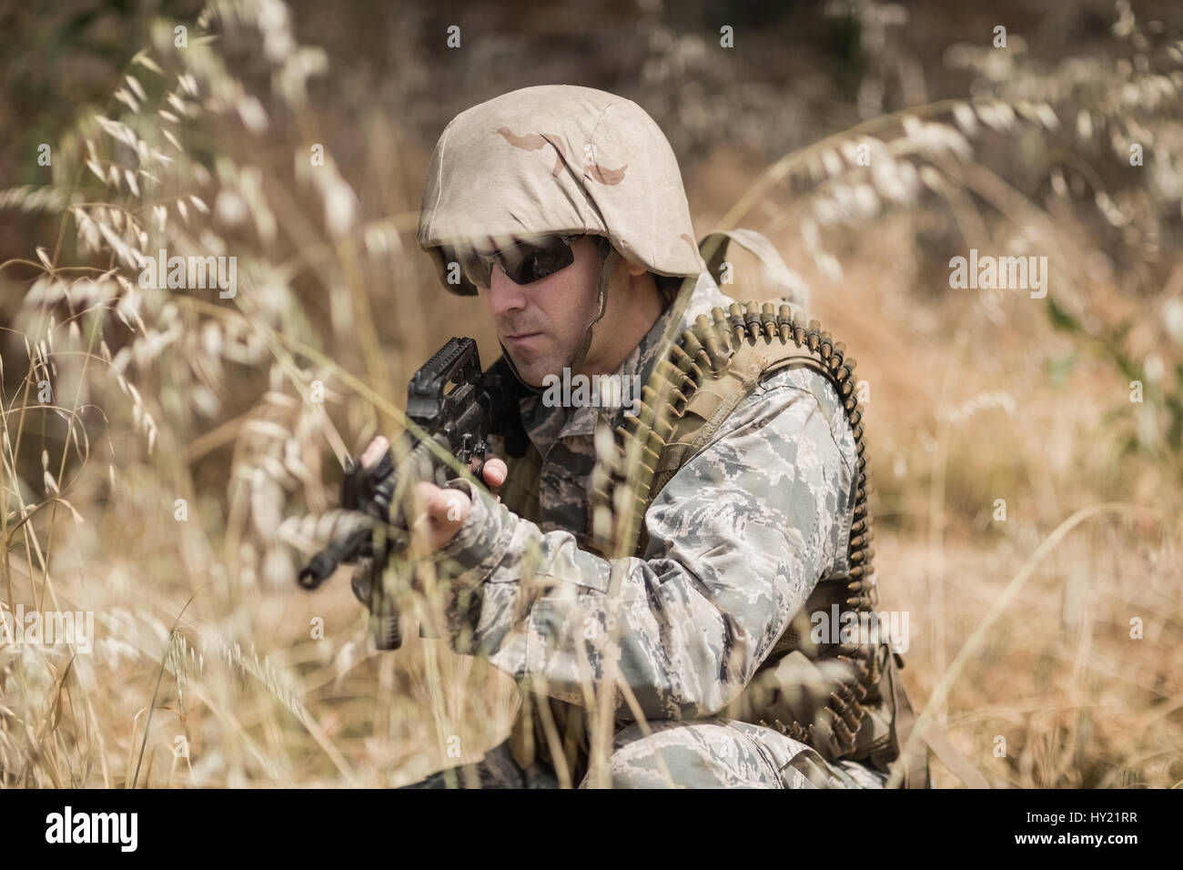 Military soldier hiding in grass while guarding with a rifle in boot