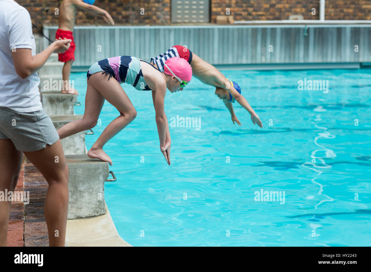 Mid section of female instructor monitoring time of children diving in