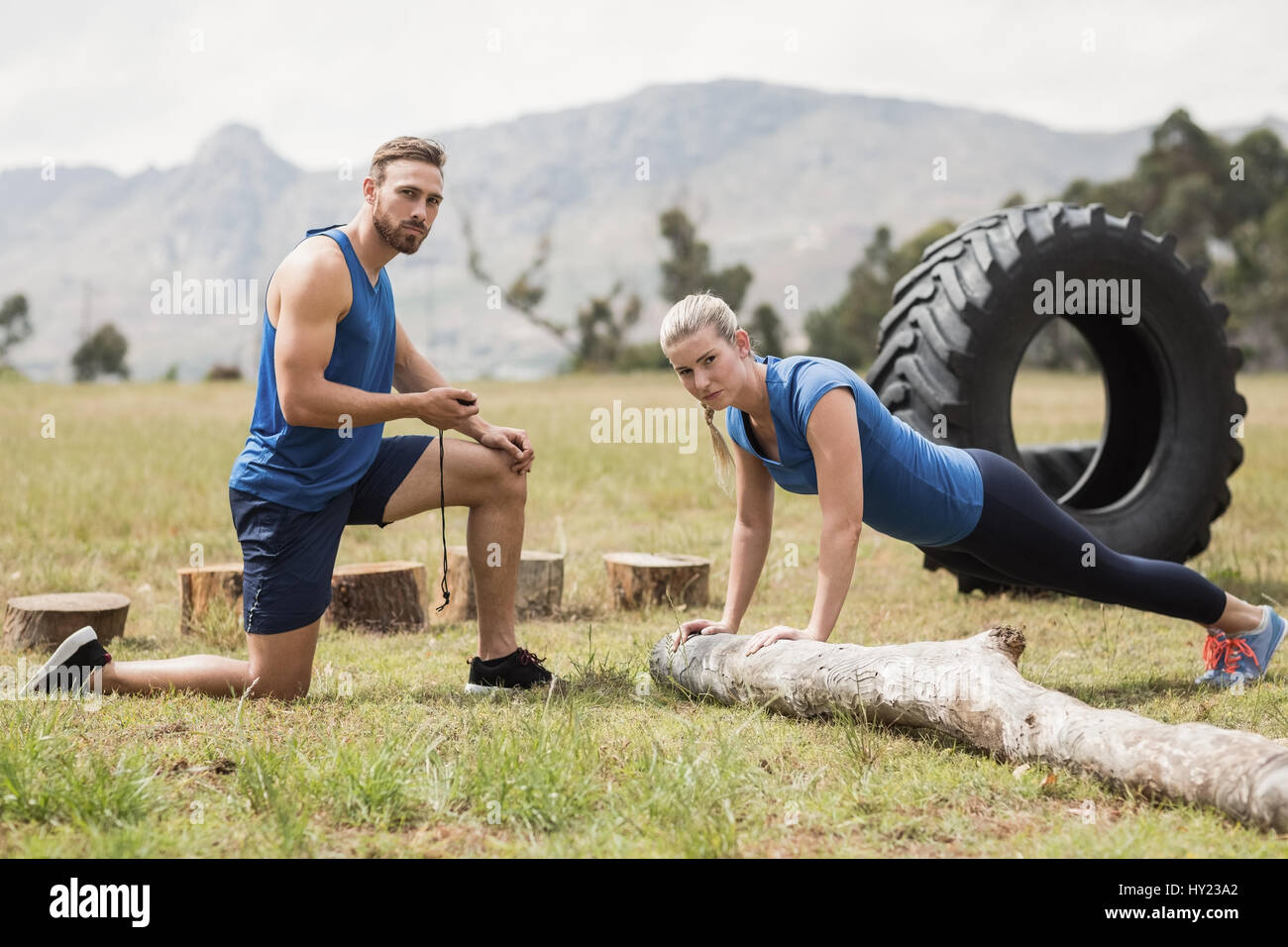 Fit performing pushup exercise while man measuring time in boot camp Stock Photo