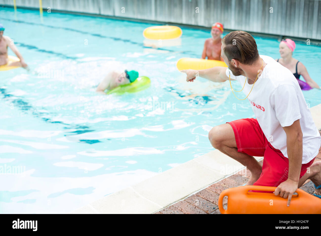 Male lifeguard assisting swimmers at poolside Stock Photo Alamy