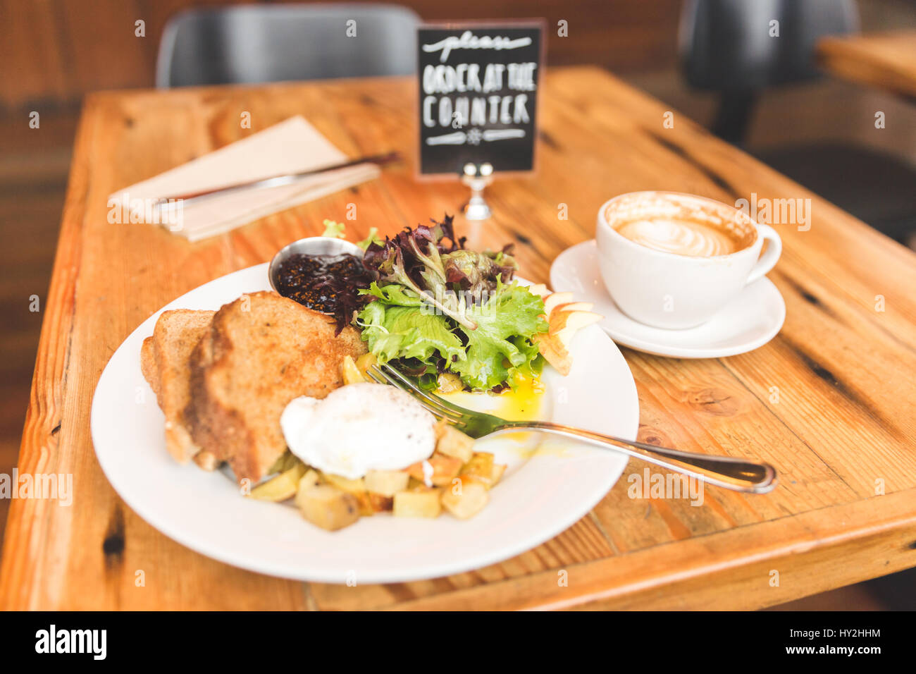 Eggs, potatoes, lettuce, toast and coffee in a breakfast meal spread. Upscale cafe setting. Stock Photo