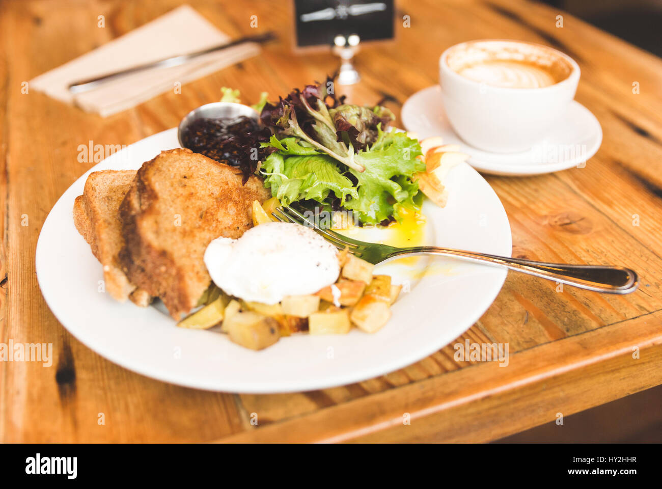 Eggs, potatoes, lettuce, toast and coffee in a breakfast meal spread. Upscale cafe setting. Stock Photo