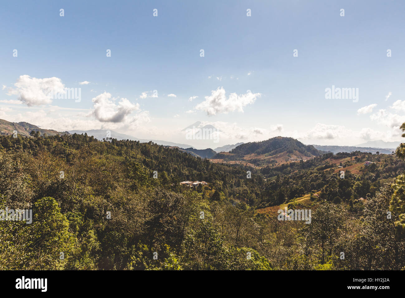 Guatemala's twin volcanoes, Fuego (left) and Acatenango (right), surrounded in clouds on a sunny day. Stock Photo