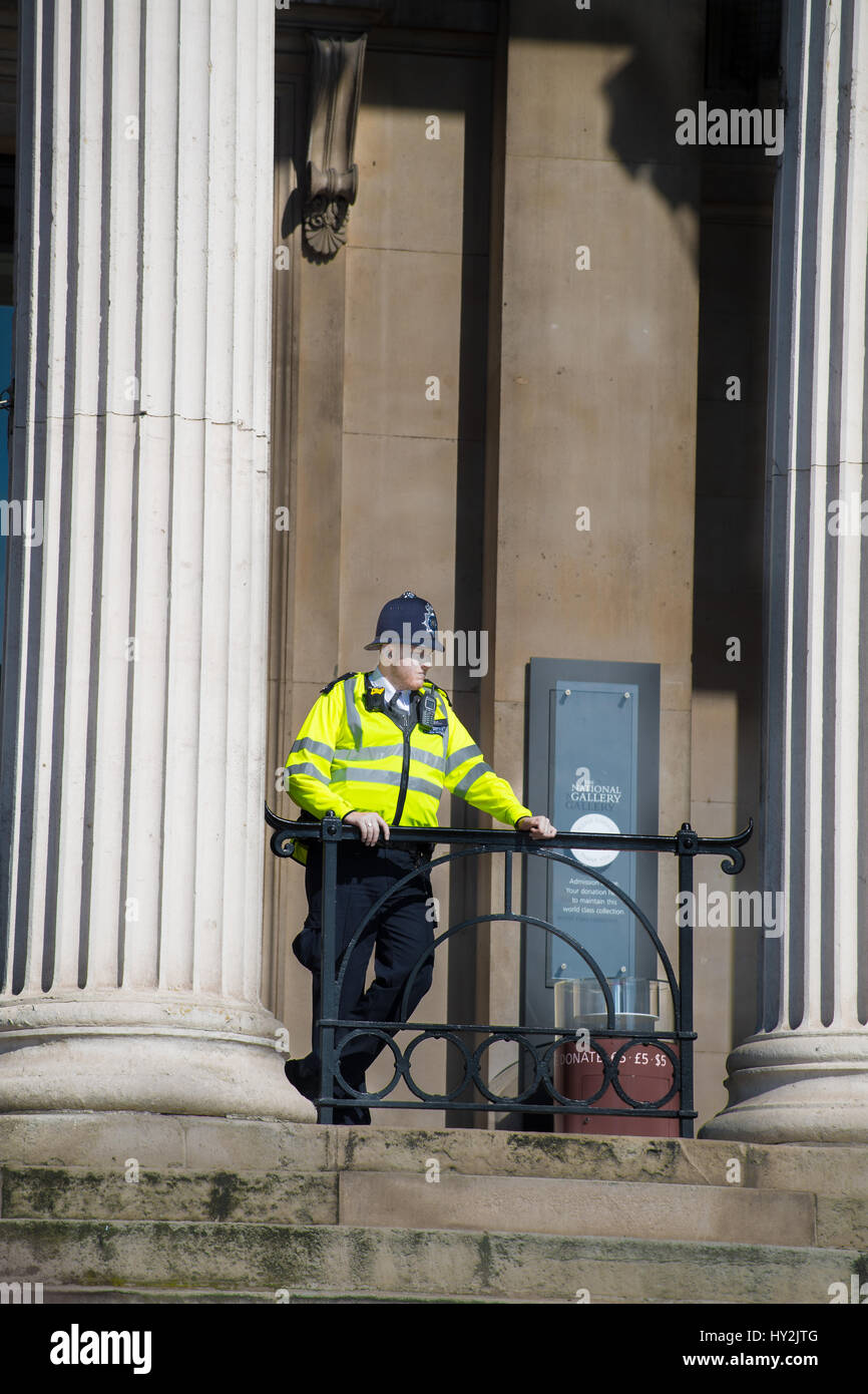 A metropolitan police officer surveys Trafalgar Square from a balcony at the National gallery London, England. Stock Photo