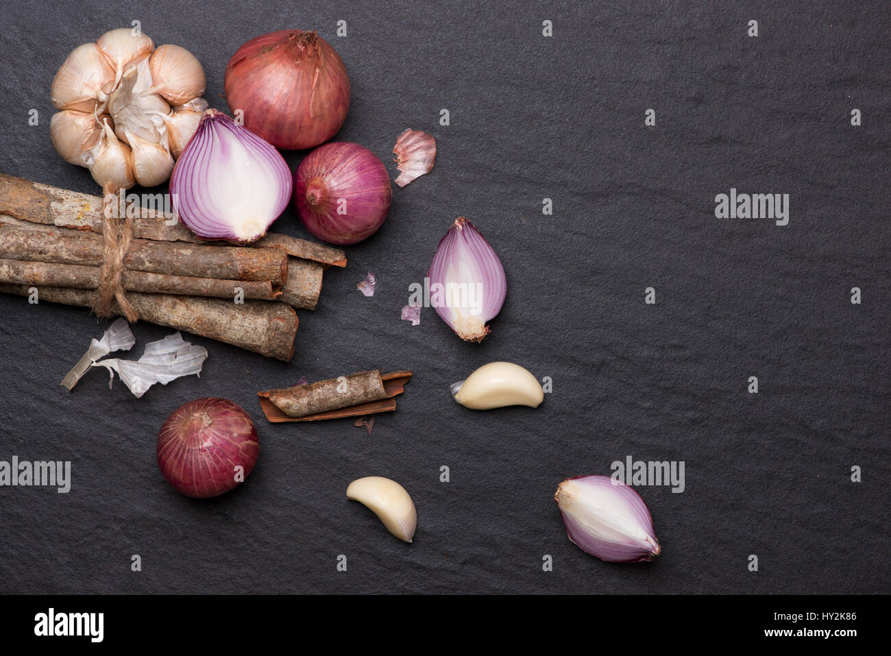 Cooking ingredients: cinnamon sticks and garlic on black stone table. Stock Photo
