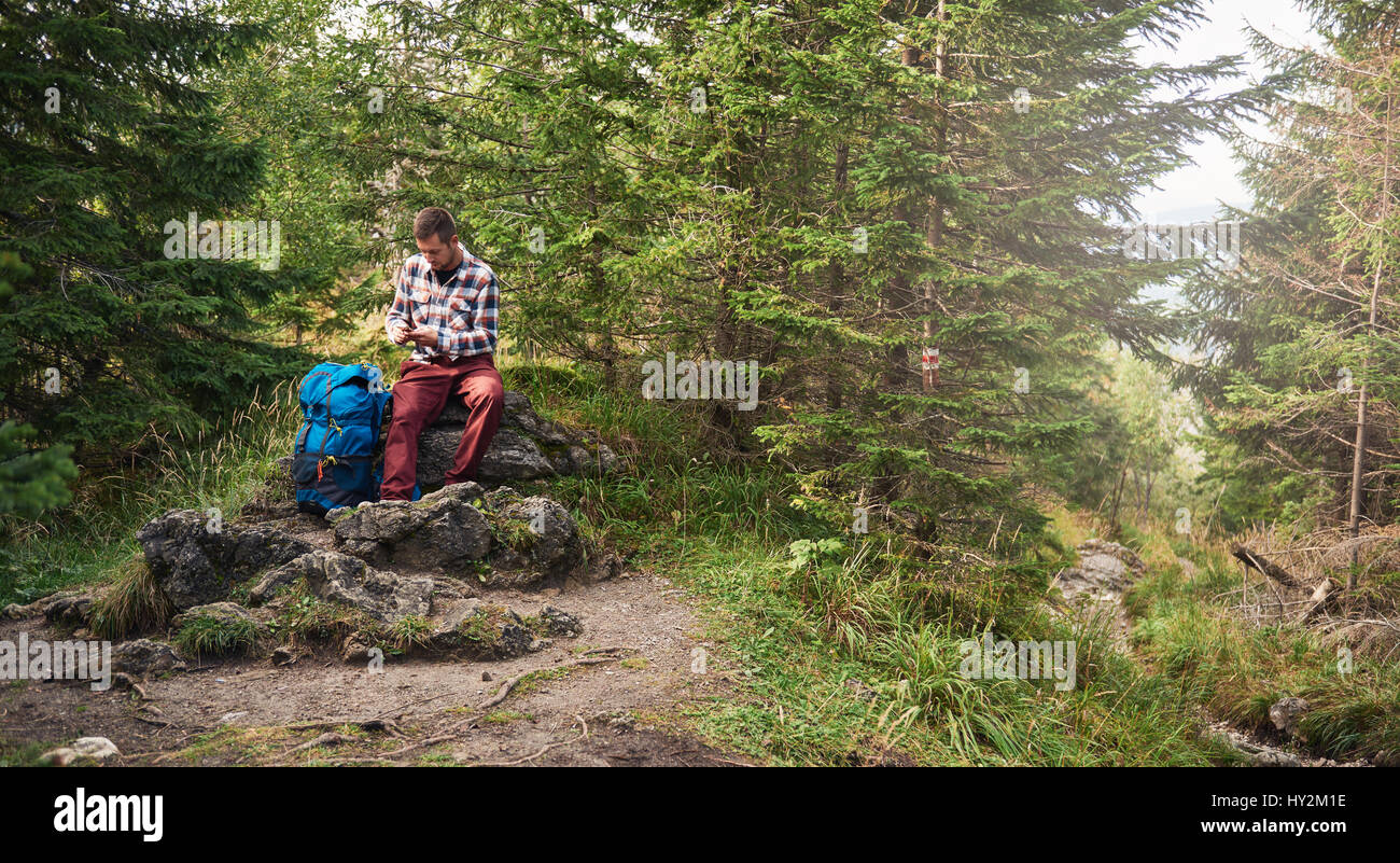 Hiker sitting on a rock using cellphone gps Stock Photo