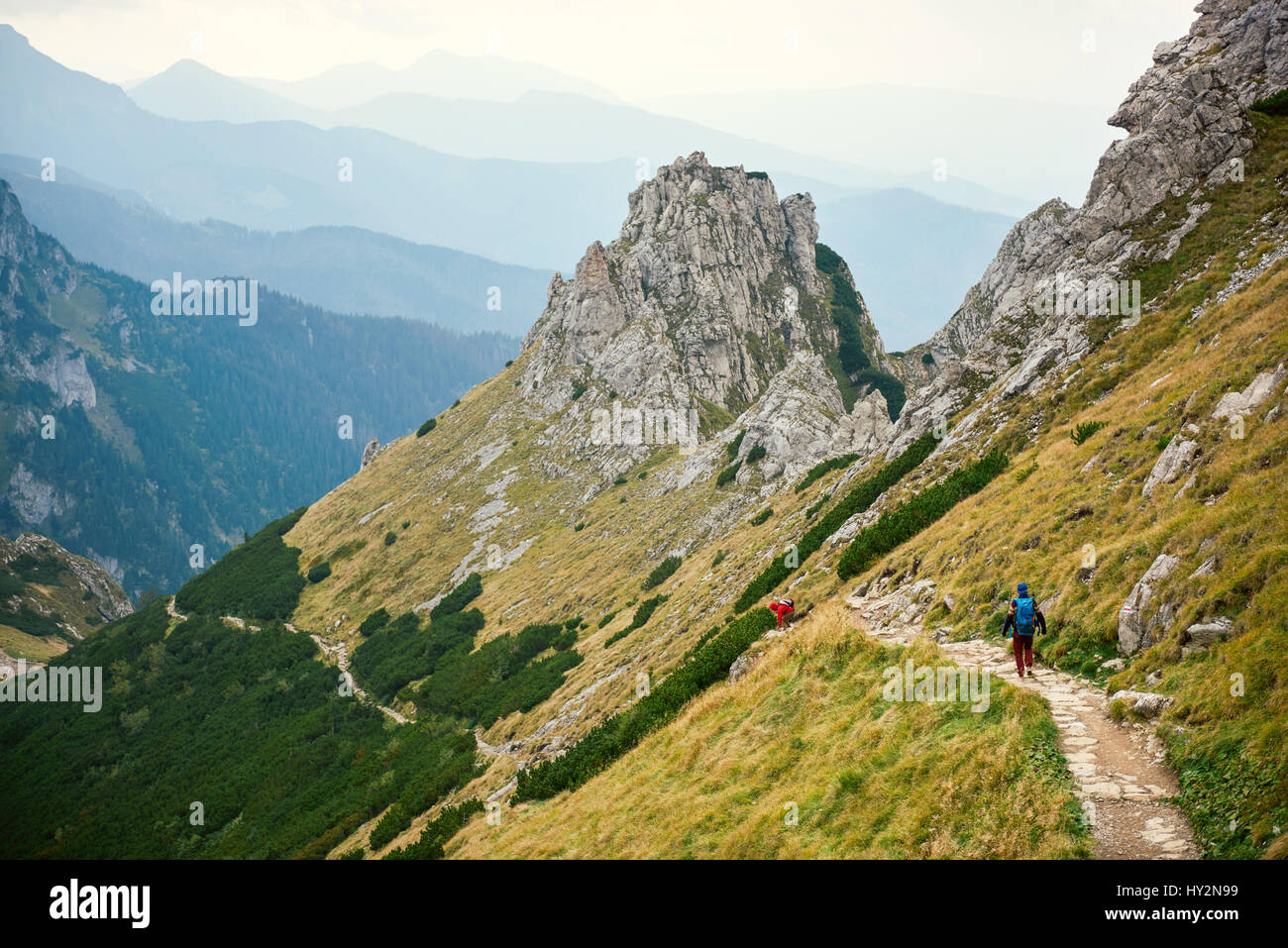 Two hikers walking along a trail in the mountains Stock Photo