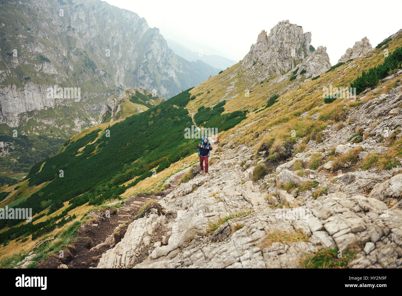 Hikers walking along a trail in rugged mountain terrain Stock Photo