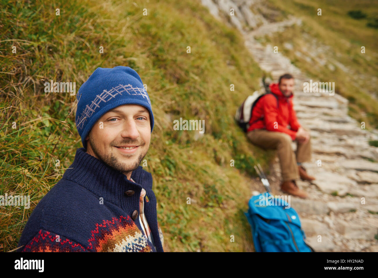 Smiling hikers resting on a rugged mountain trail Stock Photo