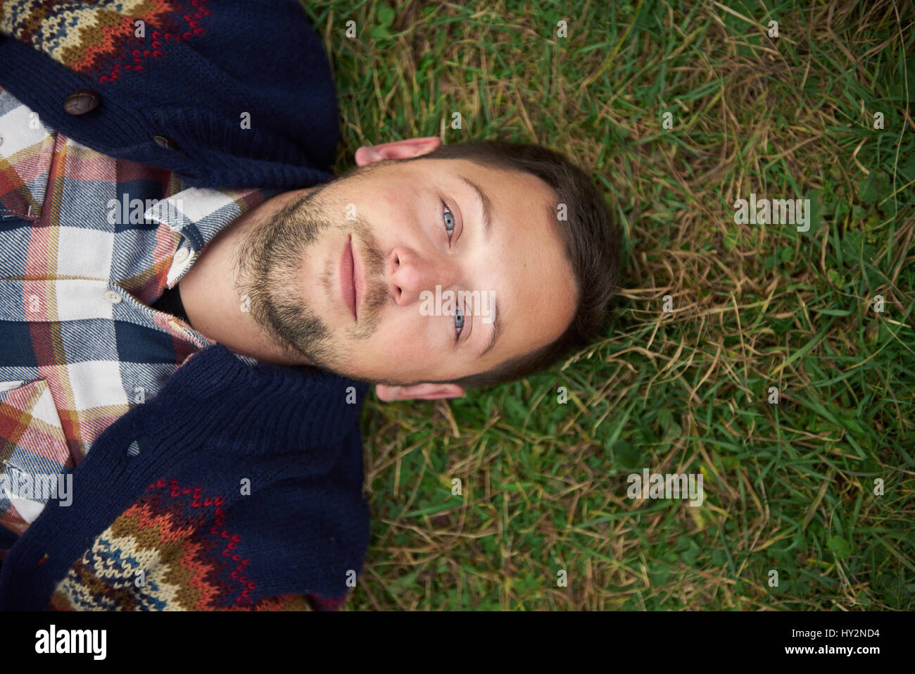 Smiling young man lying on grass in the great outdoors Stock Photo