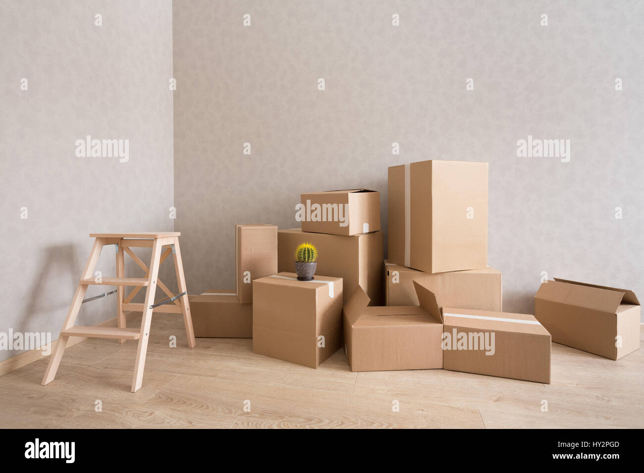 Cardboard boxes pile in new empty room with step-ladder Stock Photo