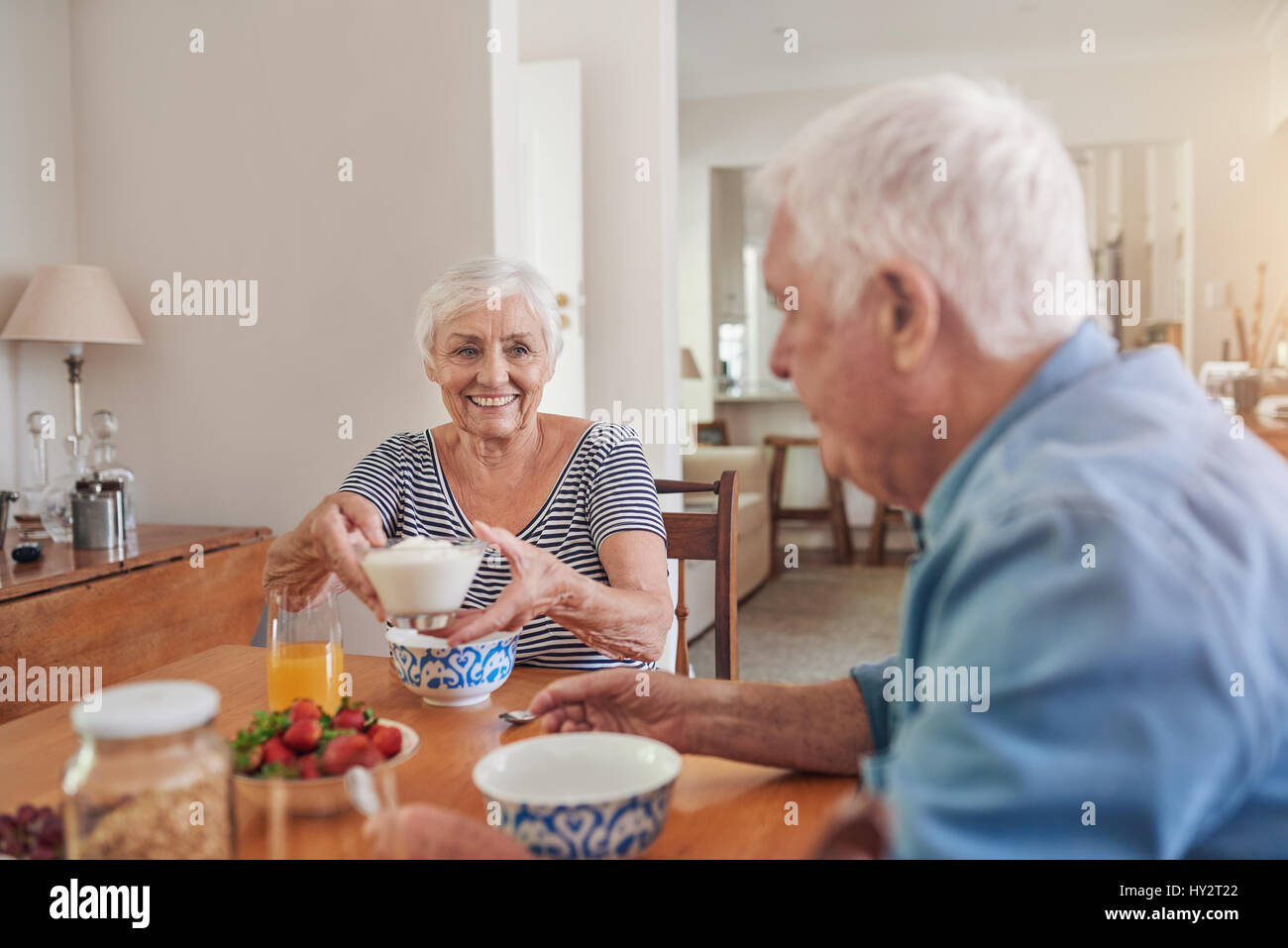 Content seniors eating a healthy breakfast together at home Stock Photo