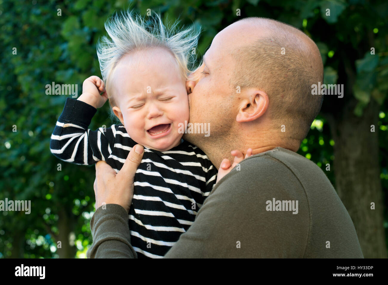 Sweden, Father kissing crying baby son (12-17 months) Stock Photo