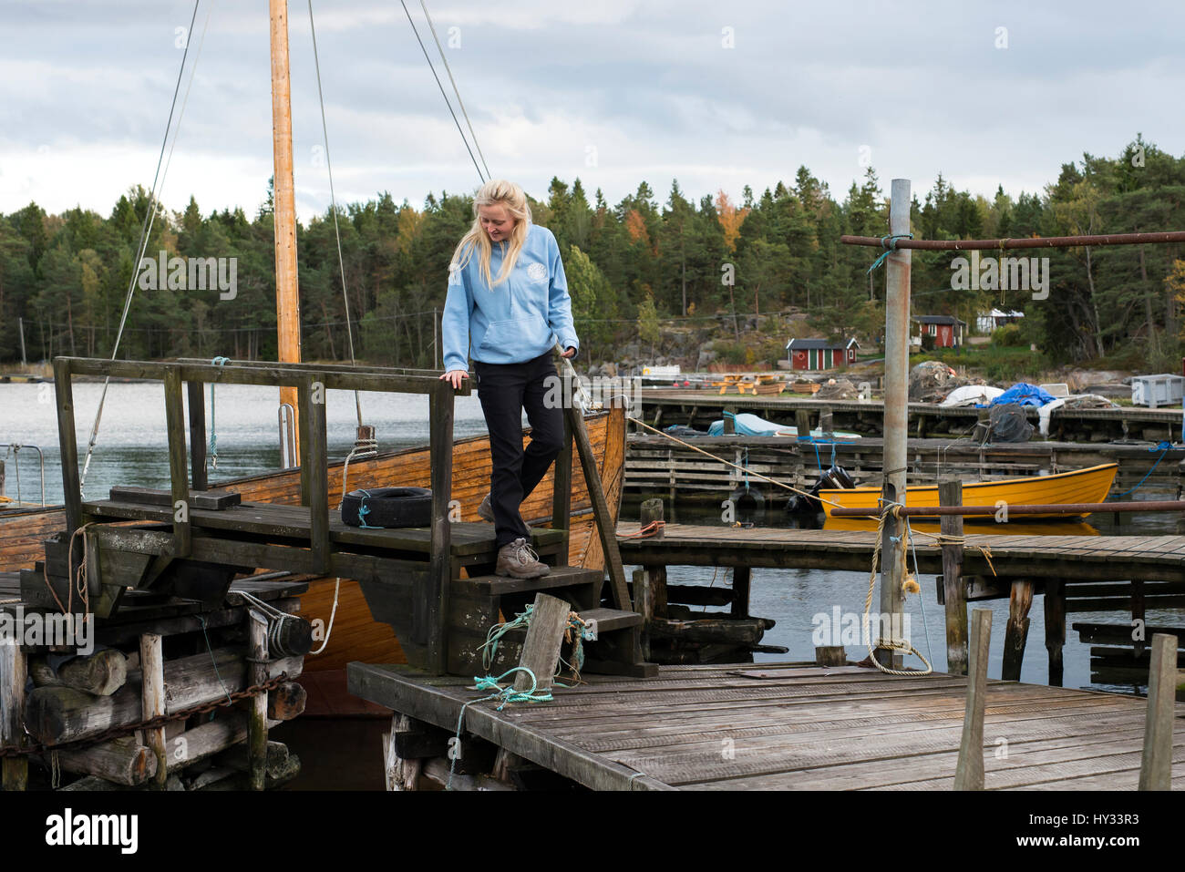 Sweden, Sodermanland, Braviken, Young woman walking on wooden dock Stock Photo