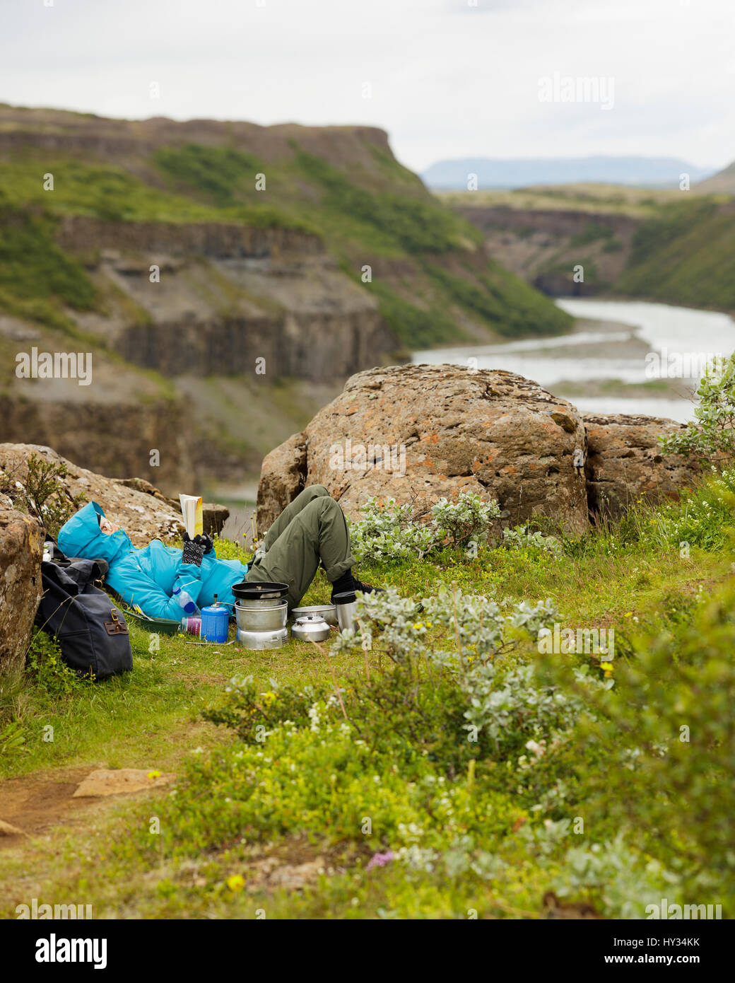 Iceland, Sudurland, Tourist lying on edge of Hvita river canyon and reading Stock Photo