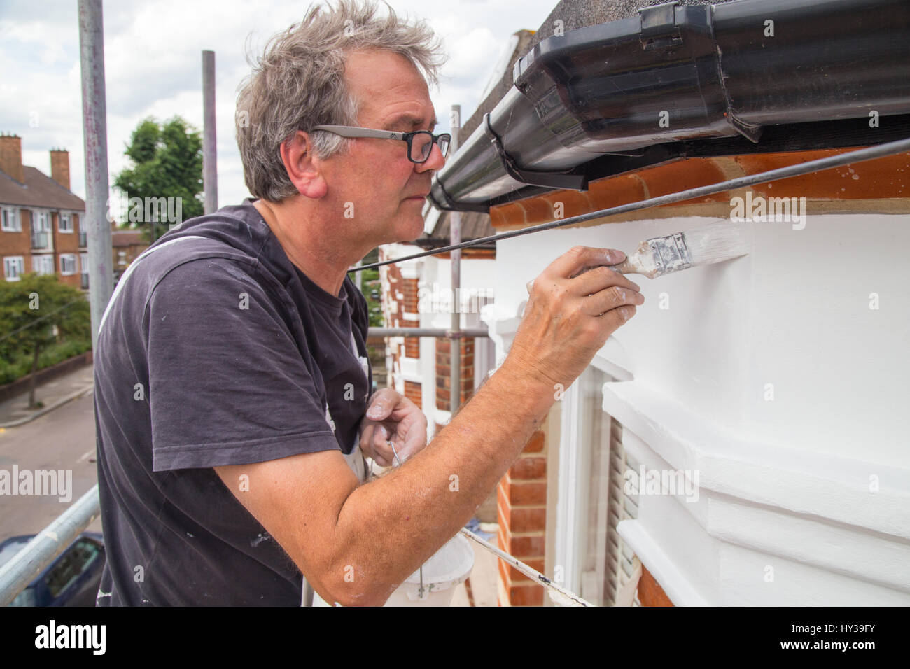 Painter And Decorator Painting The Exterior Of Victorian Terrace
