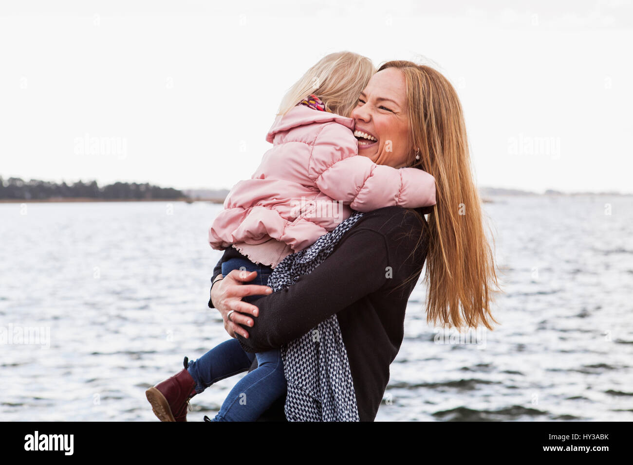 Solvesborg, Blekinge, Sweden, Mid adult woman holding girl (2-3) at seashore Stock Photo