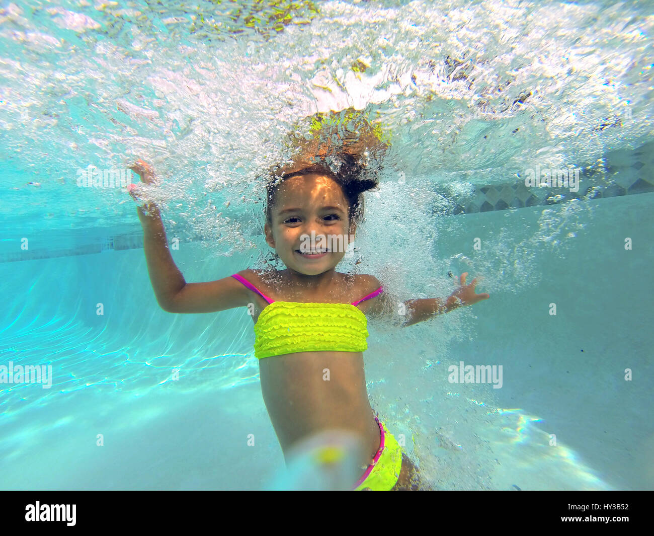 underwater in pool little girl jumps in pool smiles Stock Photo