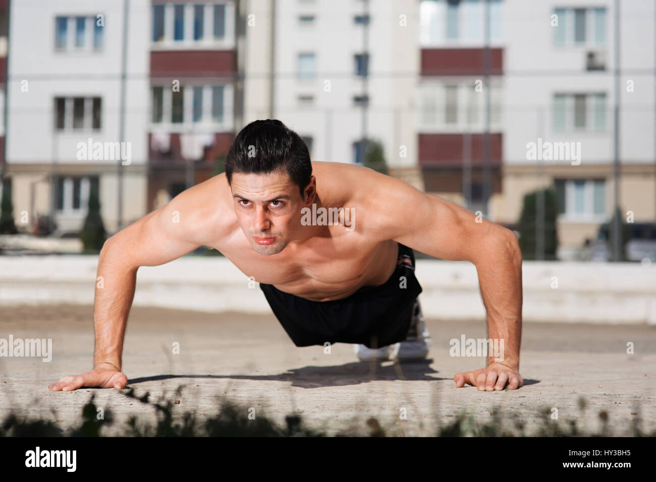 Portrait of strong young athlete push-uping outdoor in the courtyard Stock Photo