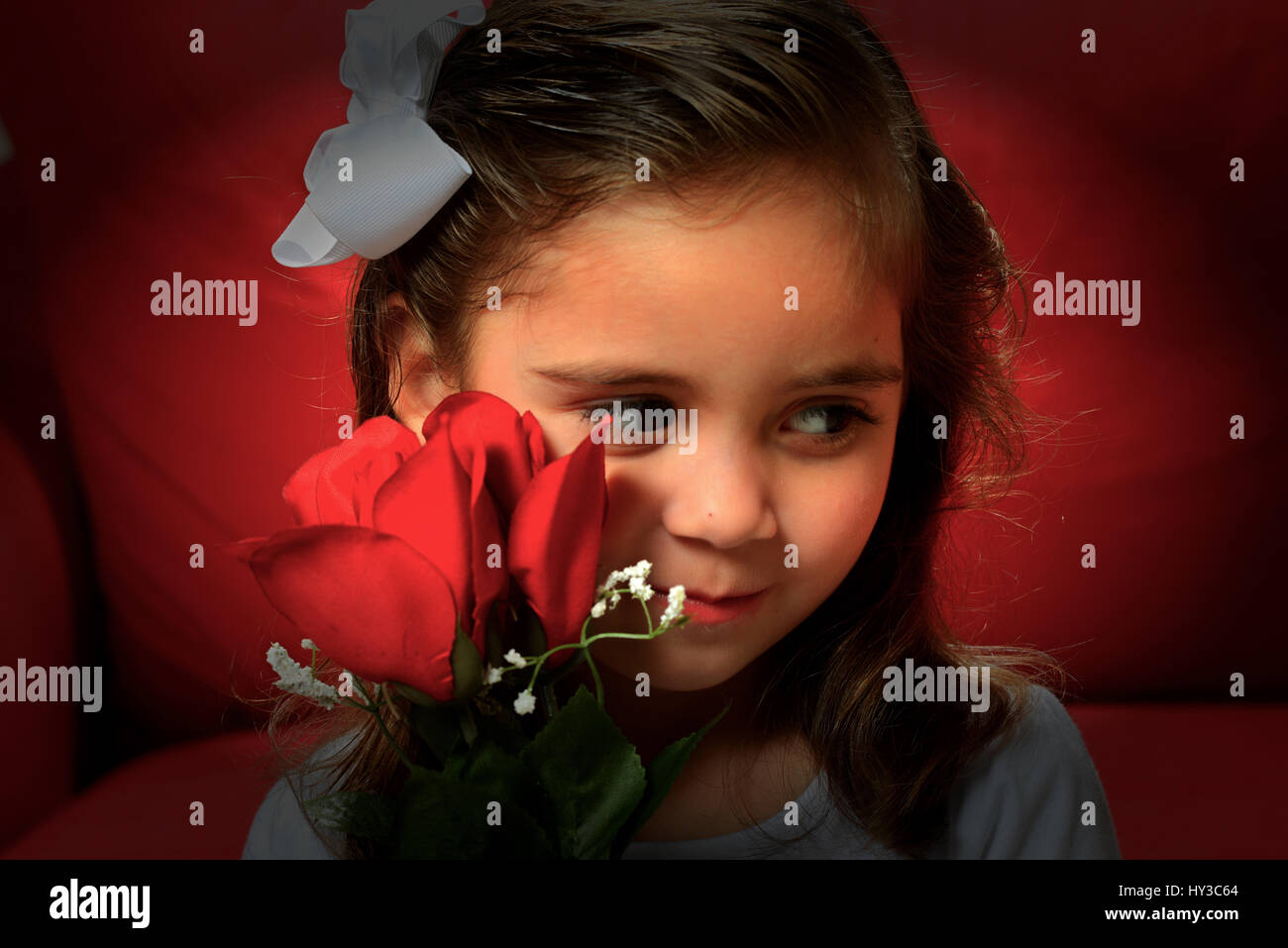 Valentines day on red sofa young girl posing with rose Stock Photo
