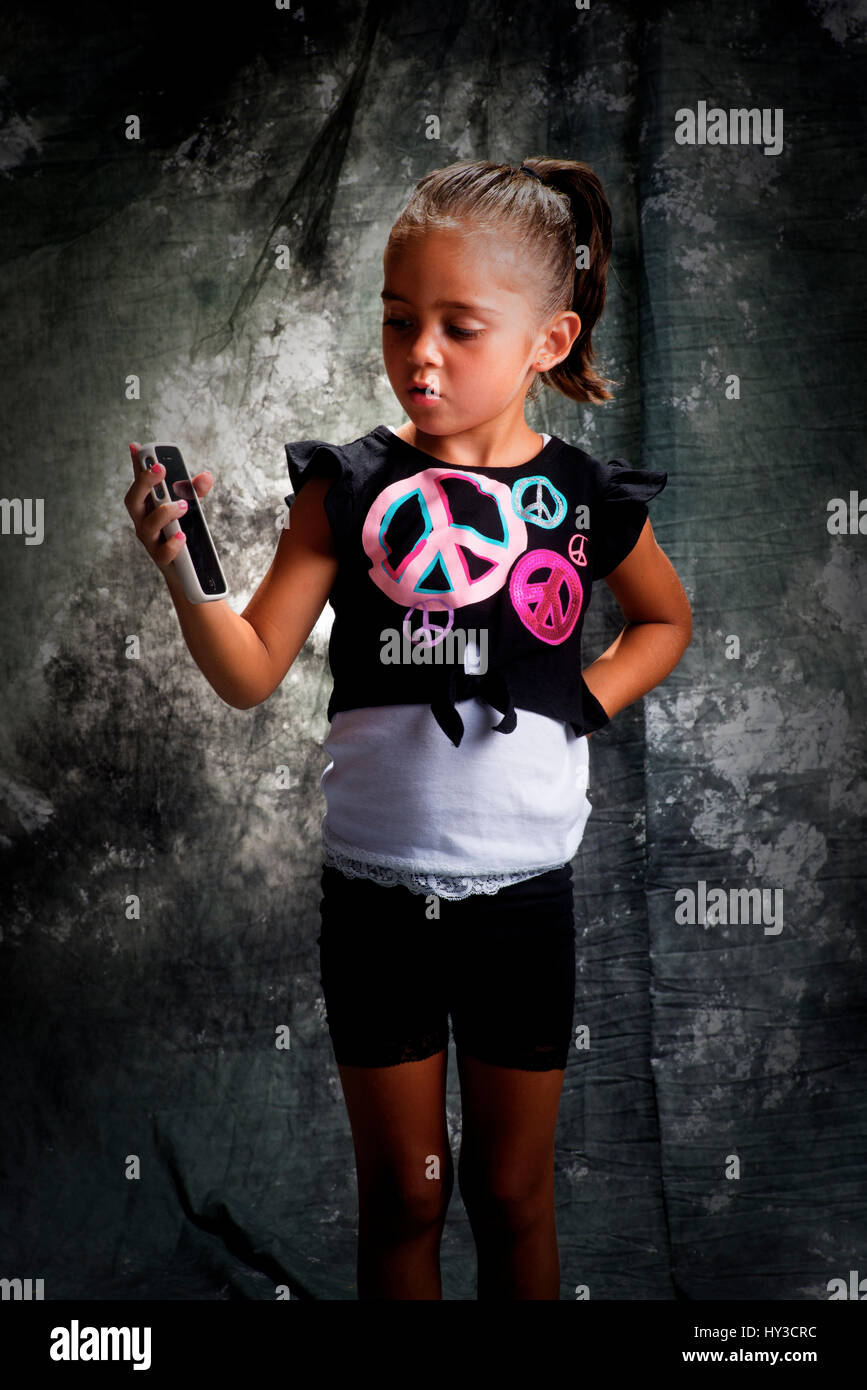 young girl in studio posing with grey background looking at phone Stock Photo