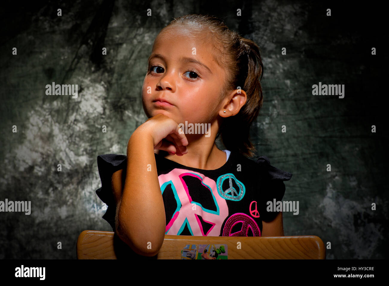 young girl in studio posing with grey background sitting down Stock Photo