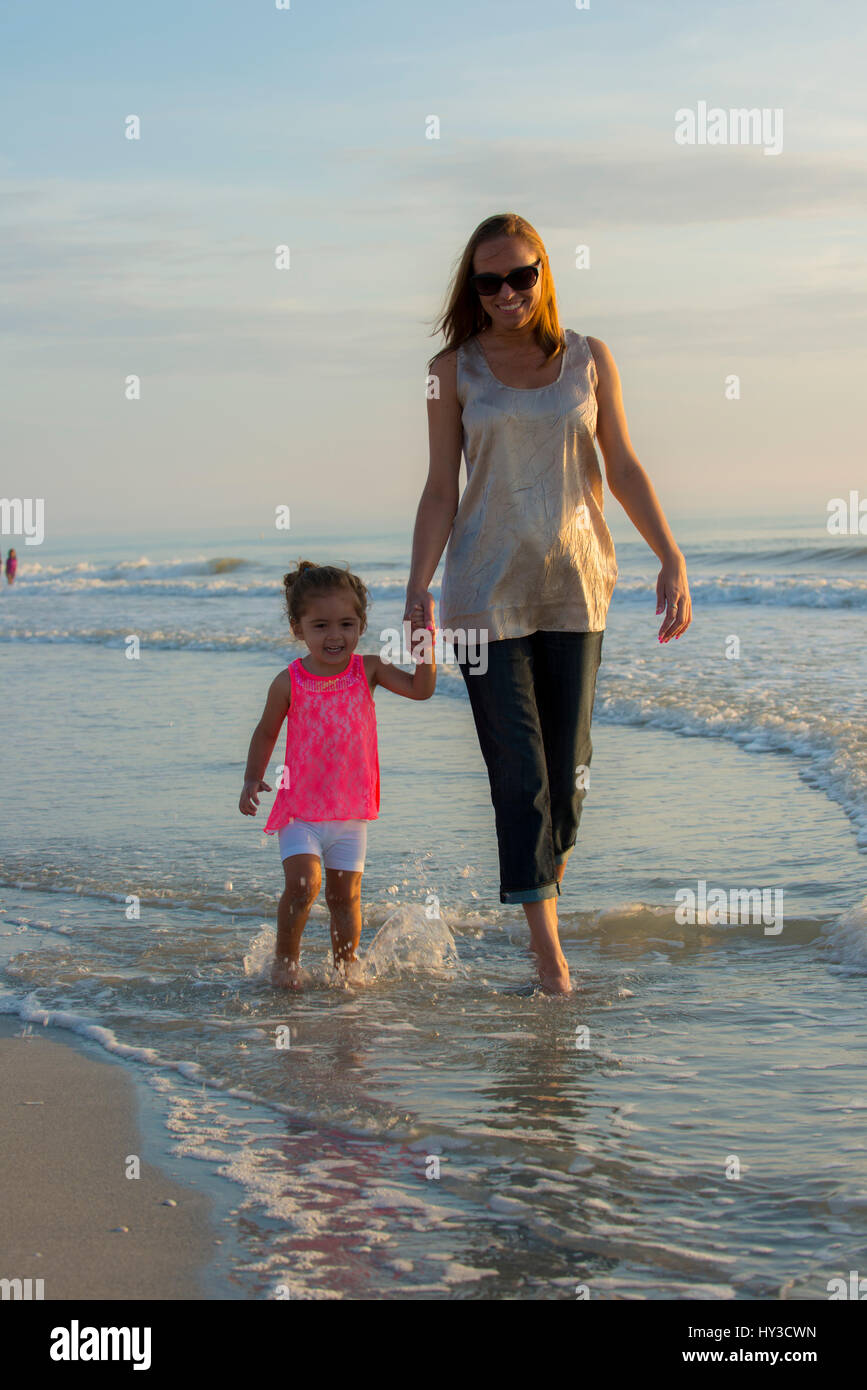 mom and daughter walking in the water Stock Photo